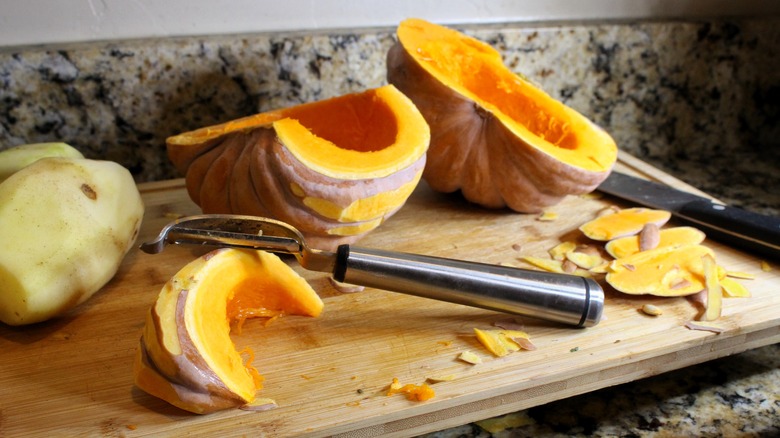 peeled pumpkin with peeler on cutting board