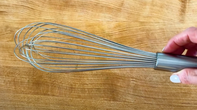 Close-up of balloon whisk against wooden cutting board