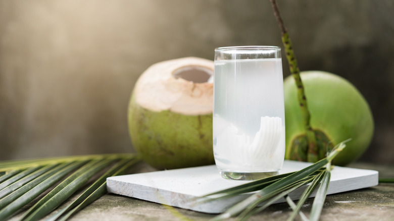 Glass of coconut water with coconuts