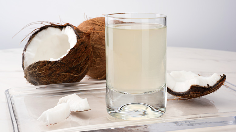 Glass of coconut water next to an open coconut