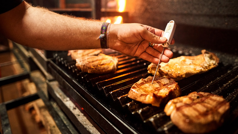 man checking meat on grill with meat thermometer