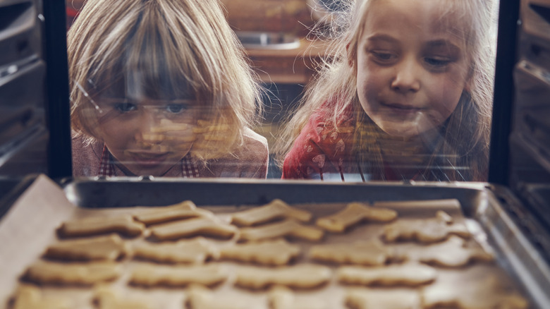 Kids watching sugar cookies baking in oven