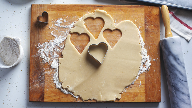 Rolled out sugar cookie dough cut into heart shapes