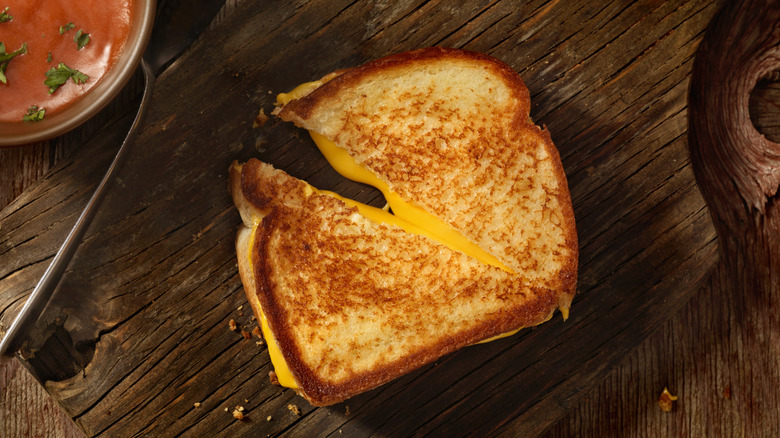 Crispy grilled cheese sandwich cut in half on wooden board