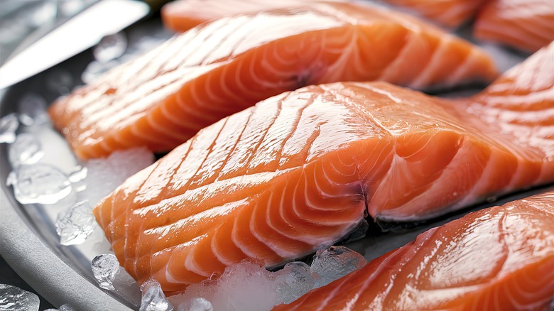 Cuts of raw salmon sit on a bed of ice