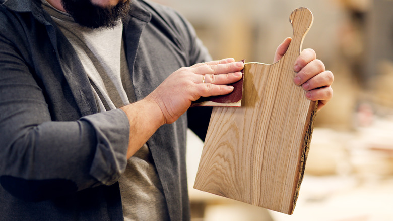 Man sanding a wooden cutting board