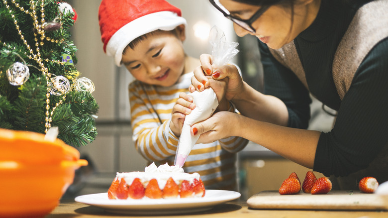 Japanese mother and son decorating a Christmas cake