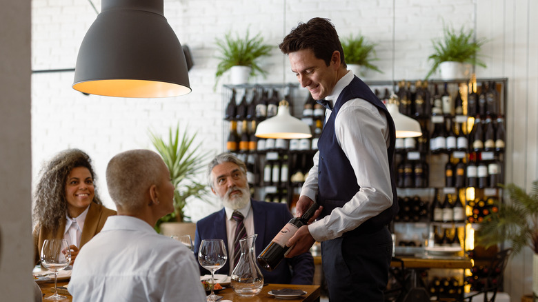 Sommelier showing wine bottle to customers