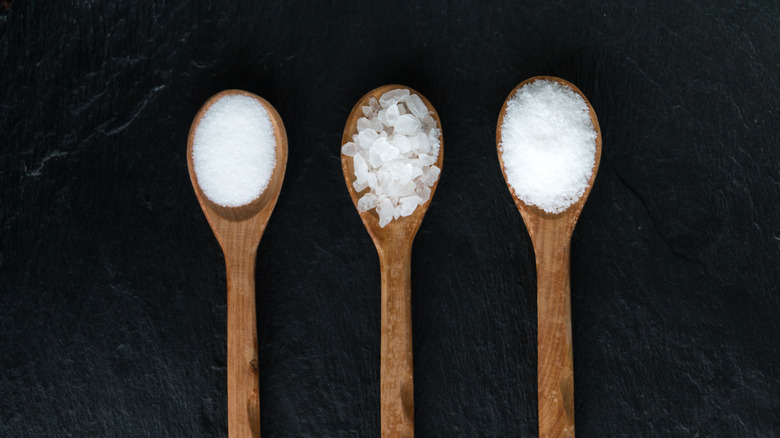 three wooden spoons with different grind salts