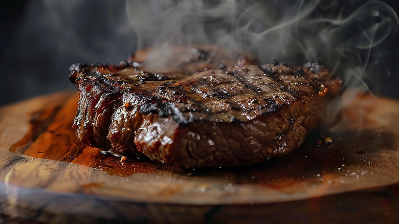 Cooked steak on wooden board with red juices running out of the meat