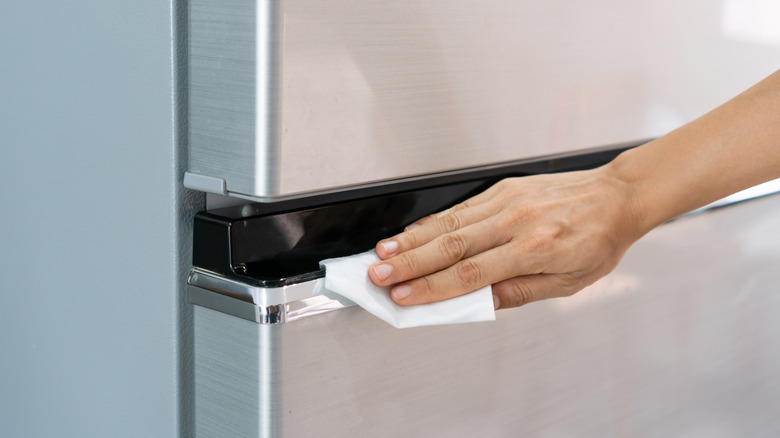 Person wiping refrigerator with a cloth