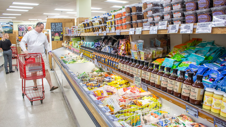 Male shopper pushes a red cart through a Trader Joe's frozen foods aisle