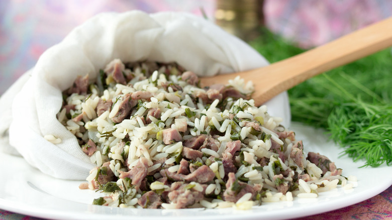 Bukharian wild rice dish with meat in cloth sack with wood spoon