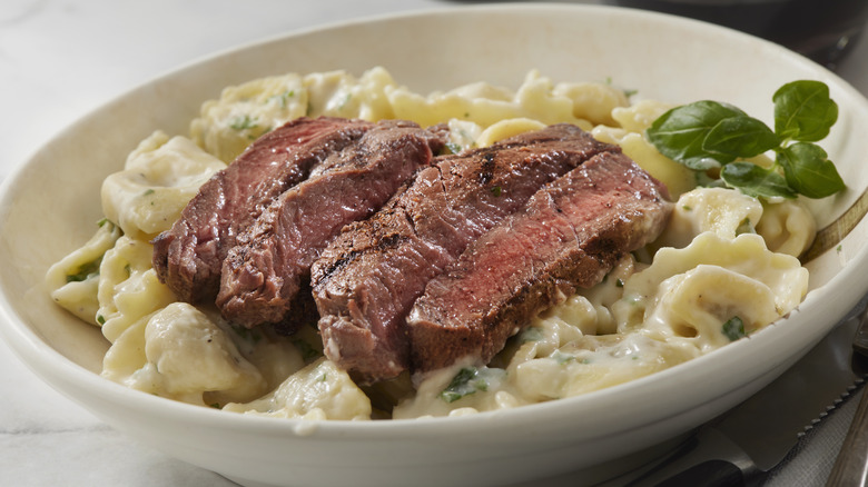 Steak and truffle tortellini with basil garnish