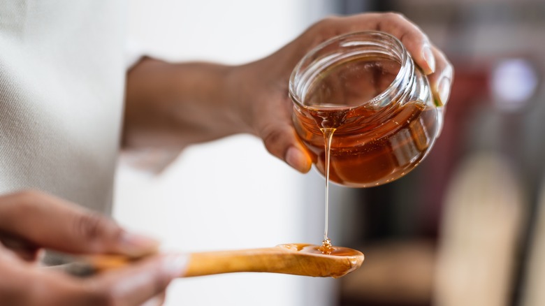 Honey pouring from glass jar to spoon