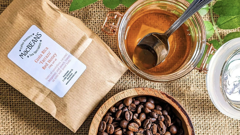 Bag of red honey coffee next to beans and pot of honey