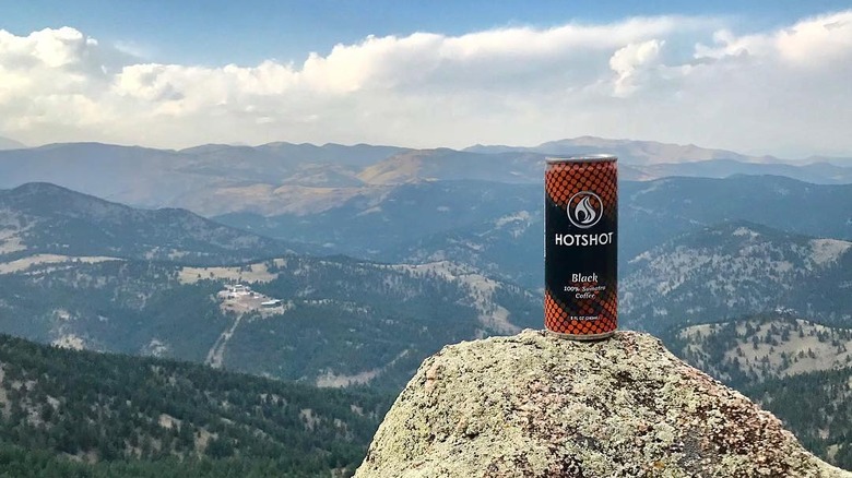 Cans of HotShot on rock overlooking mountain view