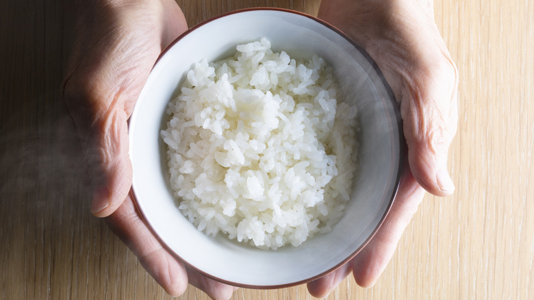 woman's hands holding bowl of white rice