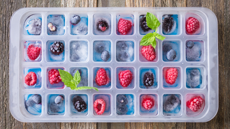 Ice tray full of ice cubes with frozen berries inside