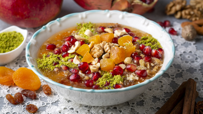 ashure in a bowl with pomegranate, dried fruits, and nuts