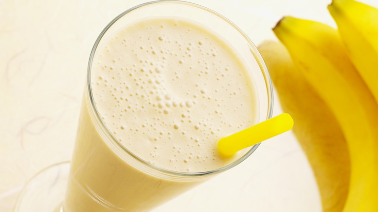 A glass of banana milk next to bananas