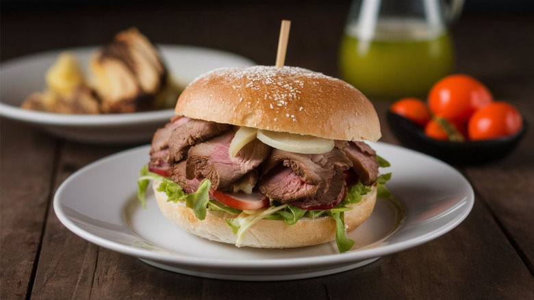 Sliced beef on a bun with lettuce, onion, and a small wooden stick through it on a white plate