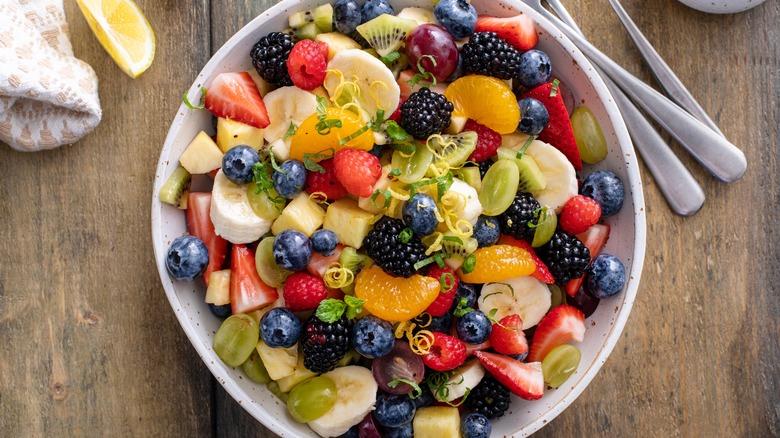 A fruit salad with apples, oranges, berries, grapes, and bananas