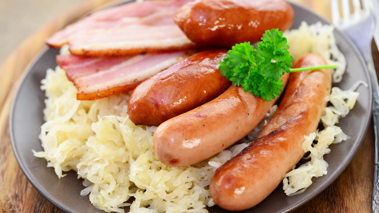 Plate of cabbage sauerkraut with slices of ham and sausages