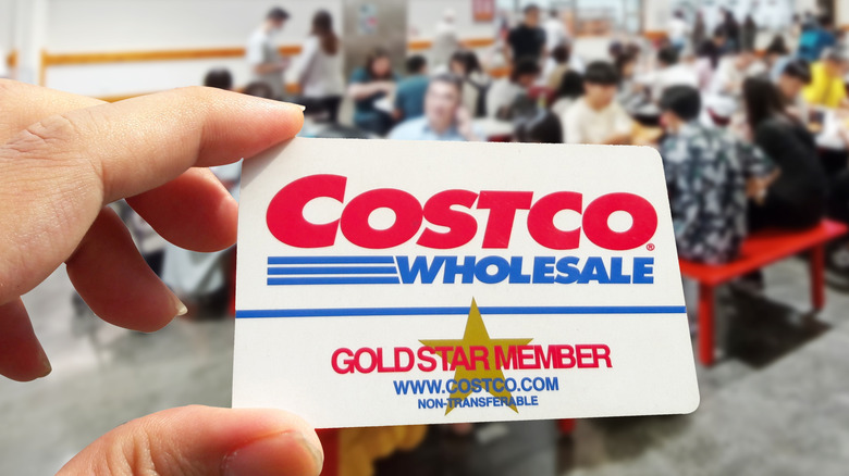 Someone holds up a Costco club card inside the food court