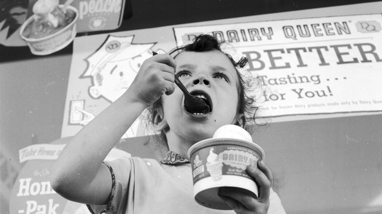 Black and white photo of a little girl eating a Dairy Queen sundae in the 50s