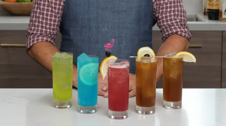 An array of Long island Iced Tea variations lined up on a white counter top