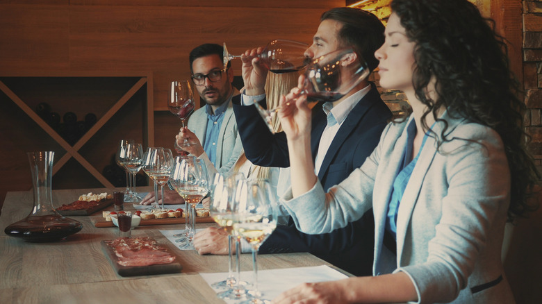 Three individuals assessing a wine as part of a formal tasting.