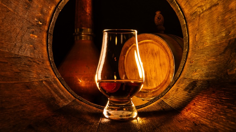 A glass of whiskey in old oak barrel