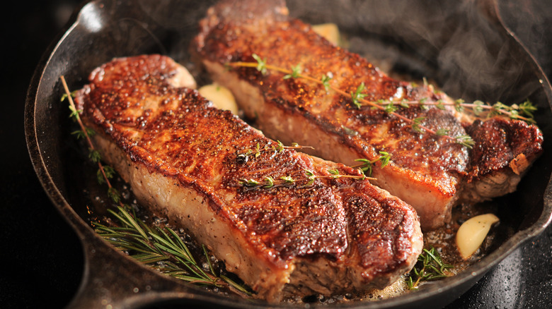 Two pork strip loins searing in a cast iron pan