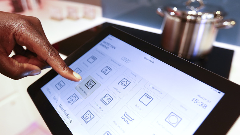 person using tablet to set oven