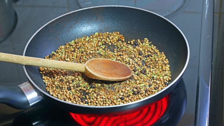 Variety of different spices being toasted in a pan