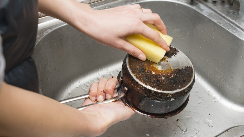 person scrubbing burnt pot