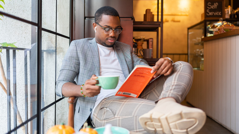 Person reads and lounges with cup of coffee