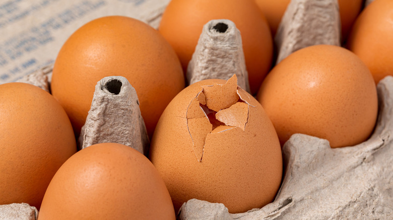 Carton of eggs with cracked egg