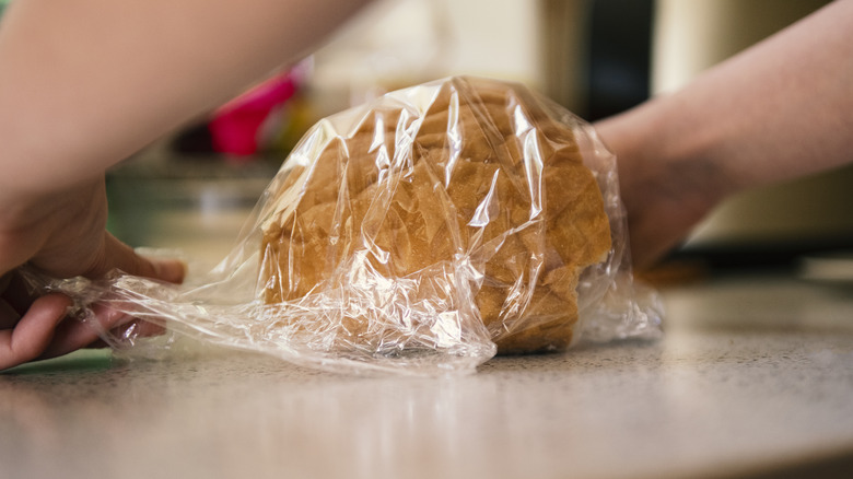 Wrapping a loaf of bread in plastic wrap