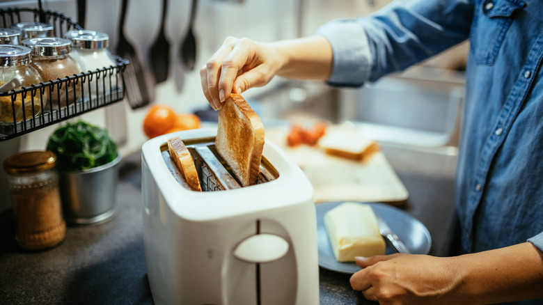 Person removing bread from toaster