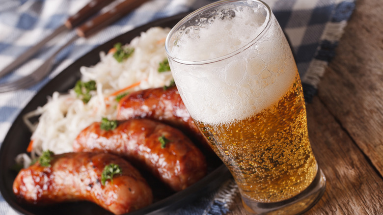 Cooked bratwurst in a pan with a glass of beer