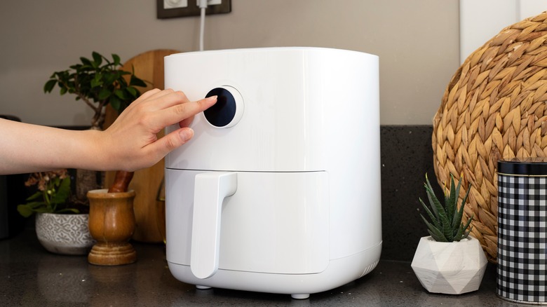Woman setting the cooking time on an air fryer