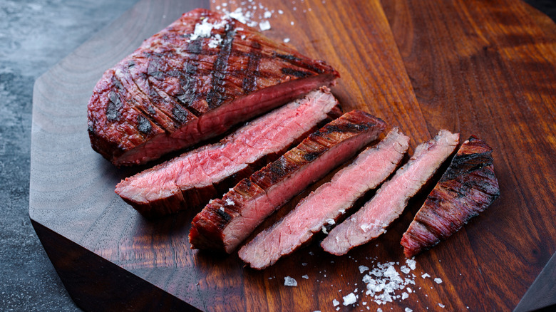 Grilled flank steak on a wooden board.