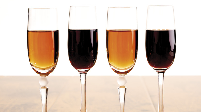 Four flute glasses with two filled with dark port wine and two with light port