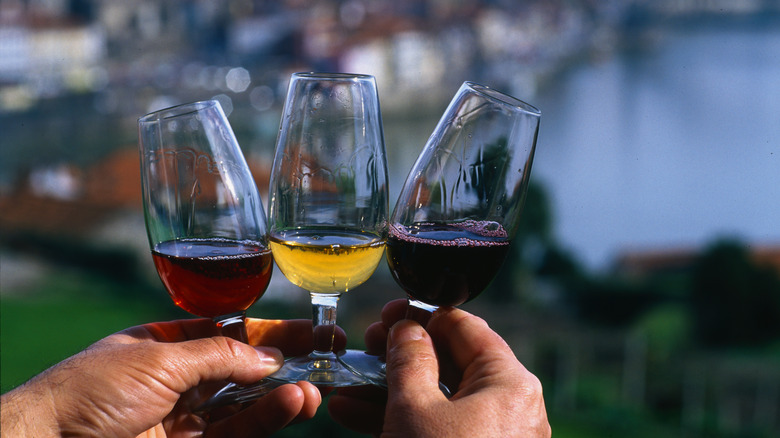 Person holding three glasses of colorful port wines