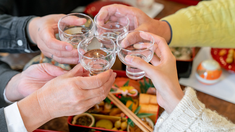 hands toasting with sake glasses