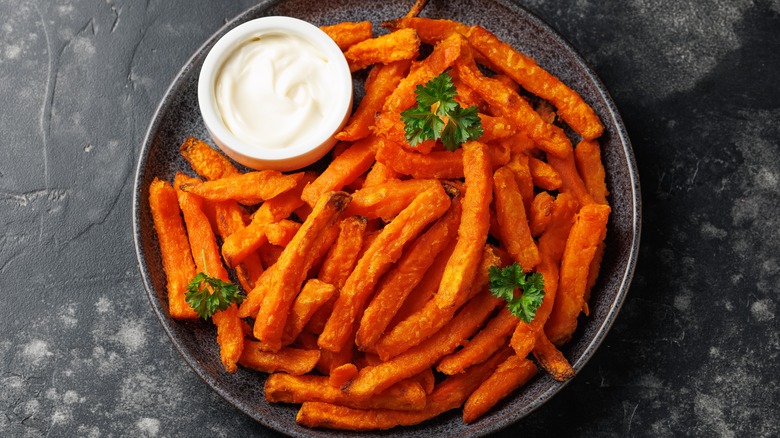 Black dish of crispy sweet potato fries with mayo dip