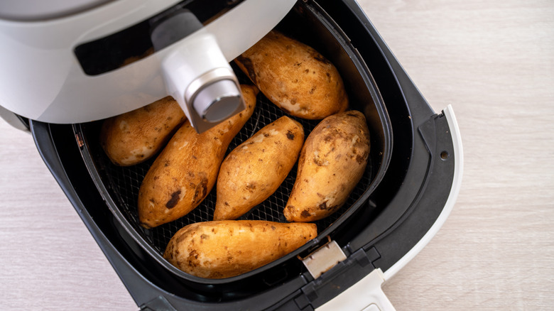 Whole sweet potatoes being cooked in an air fryer