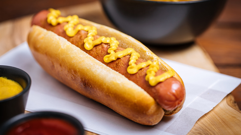 hot dog served on a bun and topped with yellow mustard